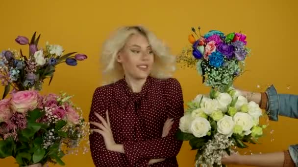 Blondes Mädchen, das mit verschränkten Armen steht, Sträuße mit überraschtem Lächeln betrachtet und Blumen schnüffelt - Filmmaterial, Video