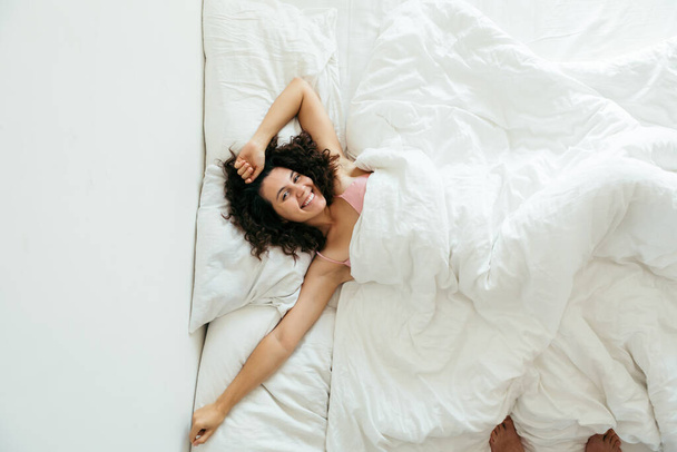 mujer bonita joven en la cama con sábanas blancas espacio de copia de luz brillante
 - Foto, imagen