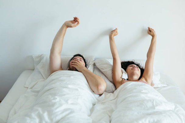 ζευγάρι κοιμάται στο κρεβάτι με λευκά σεντόνια αντίγραφο χώρο - Φωτογραφία, εικόνα