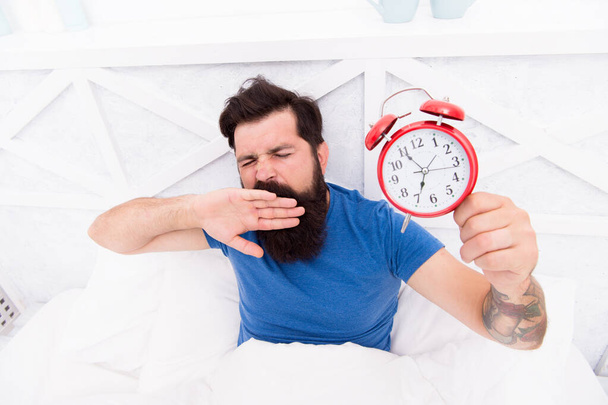 Need to Sleep longer. man hipster want to sleep. Male On Bed yawning. mute the alarm clock. the morning time. its bachelor day. Bearded guy yawning with alarm clock. Bearded man clock ticking - Foto, Imagem