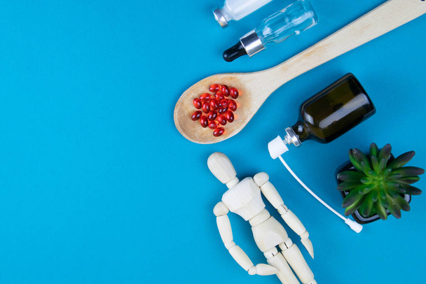 Дерев'яна іграшкова фігурка з таблетками на ложці на синьому фоні. Різні капсули, таблетки та ліки на синьому пастельному тлі. Концепція таблеток
 - Фото, зображення