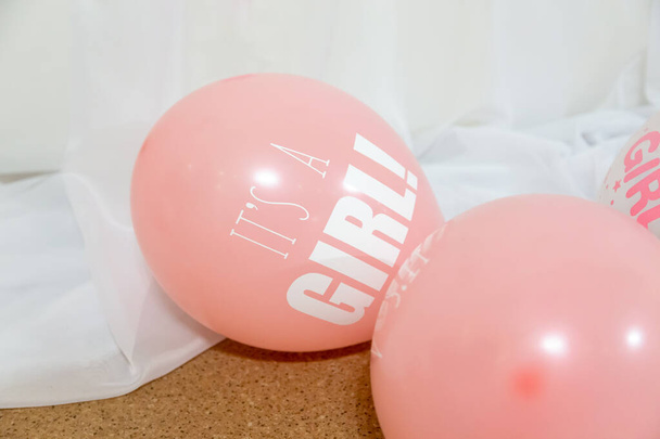 Decoración de fiesta de niña - globos blancos y rosados en las mesas con las palabras ES UNA NIÑA
 - Foto, Imagen