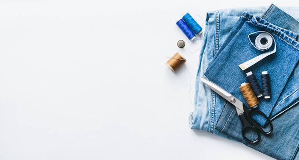 Handicraft, clothing repair. Cloth denim and sewing accessories on a white background. The concept of economical things - Foto, Bild