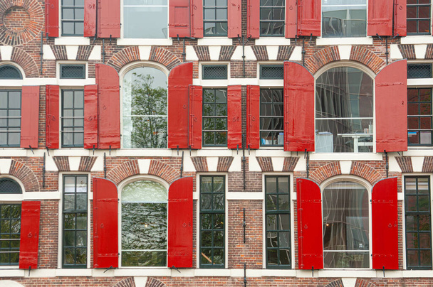 Front view of vintage windows with red wooden shutters of traditional house - Photo, image