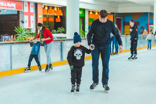 LVIV, UKRAINE - February 3, 2019: father teaching son how to skate on ski rink. family time - Photo, image