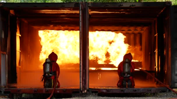 Die Sicherheit der Feuerwehrleute schützt die Gefahr durch die Hitze der Flammen mithilfe von Wassergeräten. Feuerwehrleute riskieren tapfere Karriere mit Schutzanzug und harter Mütze im Kampf mit Wasserschläuchen gegen die Hitze. Feuerwehrkonzept. - Filmmaterial, Video