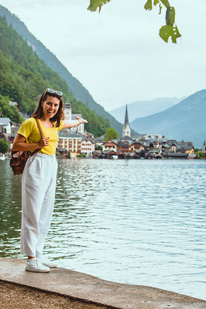 woman standing on the beach looking at hallstatt city copy space pointing to the city - Fotó, kép
