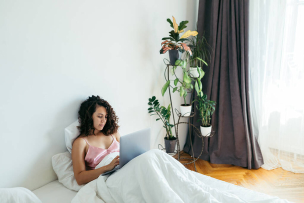 woman with laptop in bed freelancer internet shopping - Фото, изображение