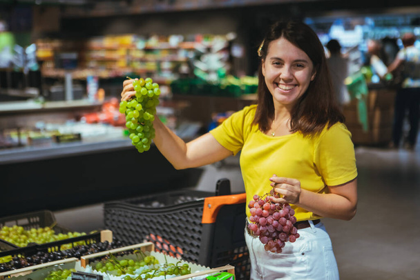 mujer compra uvas en tienda concepto de compras de comestibles
 - Foto, imagen
