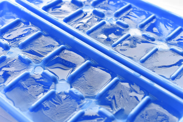 Zbliżenie wizerunek kostek lodu formujących w niebieskiej tacy kostki lodu. - Zdjęcie, obraz