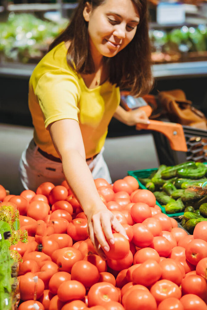 nainen valitsemalla punaisia tomaatteja myymälän hyllyltä ruokaostokset käsite
 - Valokuva, kuva