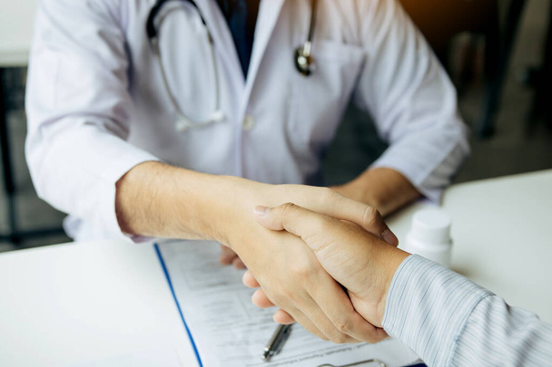 Dokter schudt handen met oudere patiënt in de kliniek kamer. - Foto, afbeelding