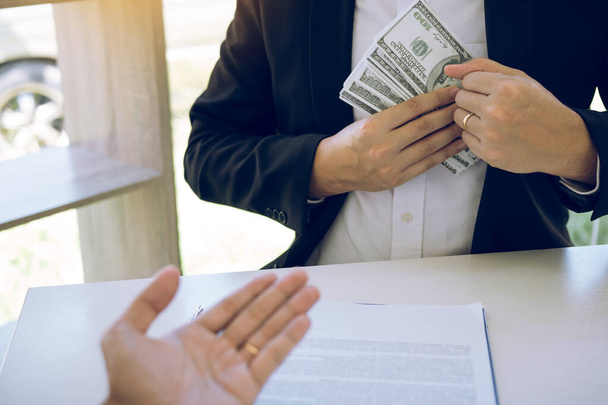 Businessman putting stack of money bills in his suit coat pocket. - Foto, afbeelding