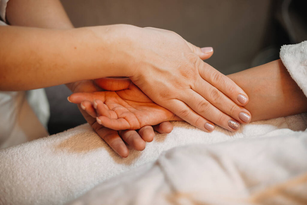 Careful masseur is massaging clients hand before starting next procedure - Foto, Bild