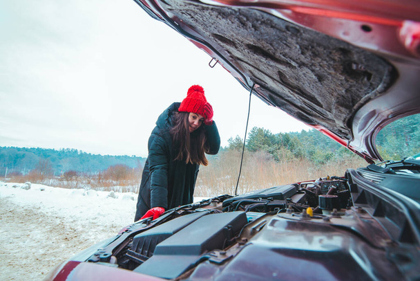 γυναίκα που εξετάζει αυτοκίνητο κινητήρα οδική βοήθεια έννοια χειμερινή περίοδο - Φωτογραφία, εικόνα