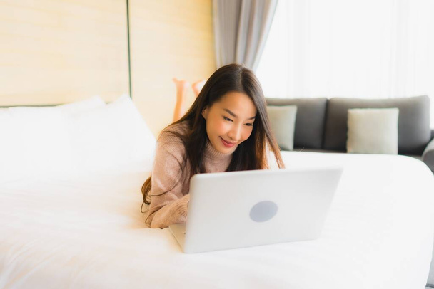 Portré gyönyörű fiatal ázsiai nő használ laptop dolgozik az ágyban a hálószoba belső - Fotó, kép