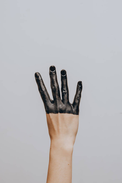 Elegant female hand dipped in black paint on a light background. Isolated. Gesture. - Photo, Image