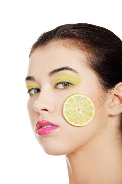 Beautiful woman's face with lime on cheek. - Zdjęcie, obraz