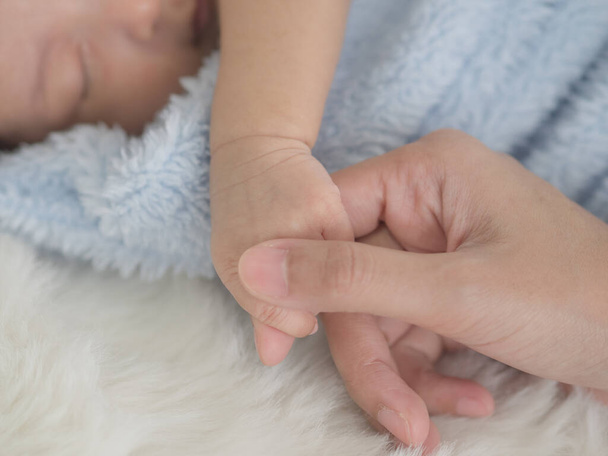 Moeder houdt de hand van de baby zachtjes vast om hem te troosten en geeft hem een veilig slaapgevoel. - Foto, afbeelding