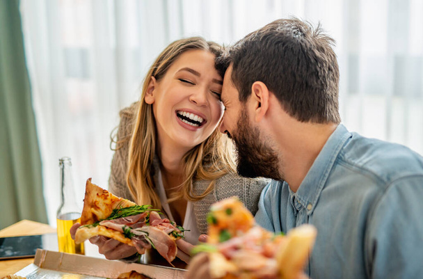 Detailní fotografie mladého páru těší v pizze doma. Pár jíst pizzu na oběd.Lidé, láska, jídlo a štěstí koncept. - Fotografie, Obrázek