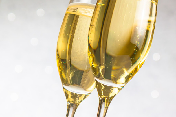 detail of a pair of flutes of golden champagne on silver bokeh - 写真・画像