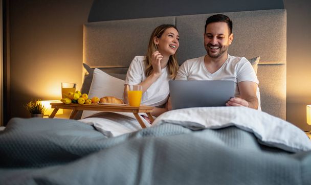 Portret szczęśliwej pary leżącej w sypialni i jedzącej razem śniadanie.Ludzie, miłość, szczęście i koncepcja stylu życia. - Zdjęcie, obraz