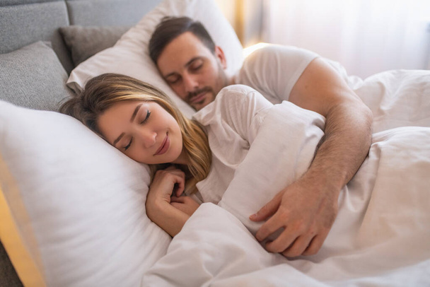 幸せなカップルは自宅でベッドで寝ています.ベッドで一緒に寝て若いかわいいカップル.ロマンチックな瞬間. - 写真・画像