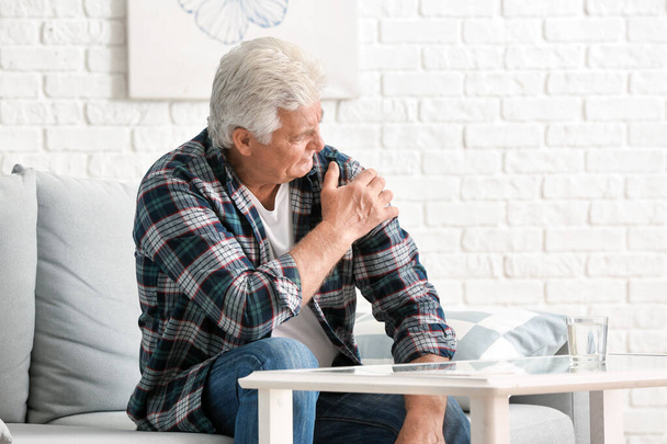 Vanhempi mies, joka kärsii Parkinsonin oireyhtymästä kotona
 - Valokuva, kuva