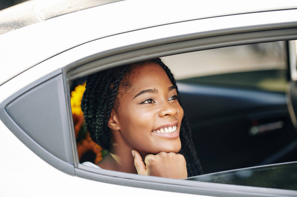 Gyönyörű fiatal fekete nő mosolyog, és néz be nyitott autó ablak - Fotó, kép