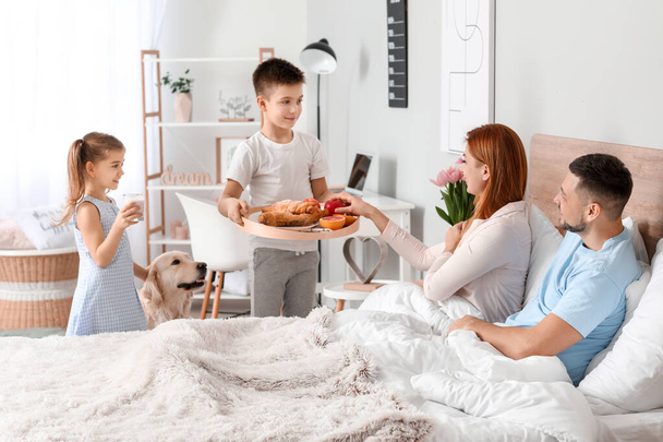 Маленькие дети приносят своим родителям завтрак в постель
 - Фото, изображение