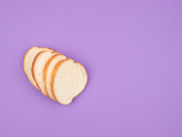 Fehér kenyeret szeletelt lila alapon. A kilátás felülről. - Fotó, kép