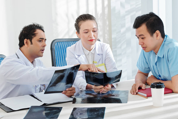Група серйозних медичних працівників, які обговорюють рентген грудної клітини пацієнта з пневмонією або раком легенів
 - Фото, зображення