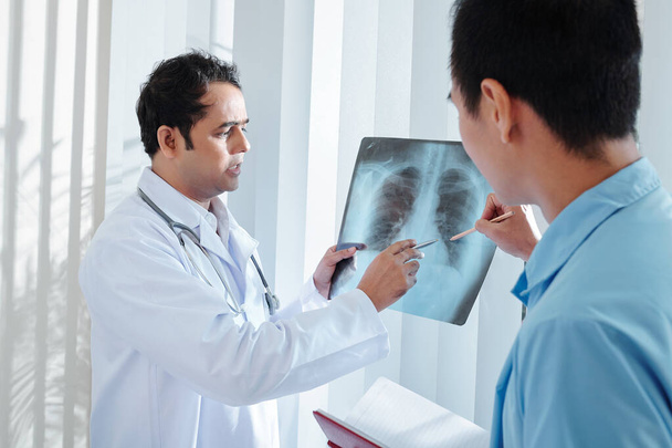 Seriöser Arzt zeigt Kollegen Lungen-Röntgen und bespricht möglichen Fall von Coronavirus oder Lungenentzündung - Foto, Bild