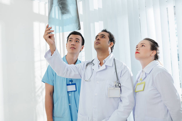Equipo multiétnico de trabajadores sanitarios que analizan la radiografía pulmonar del paciente enfermo y diagnostican un caso de coronavirus
 - Foto, imagen