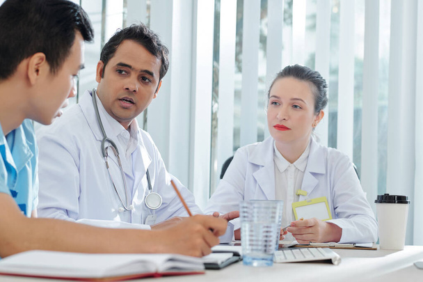 Médicos preocupados mirando a su compañero de trabajo hablando de la propagación de la epidemia
 - Foto, imagen