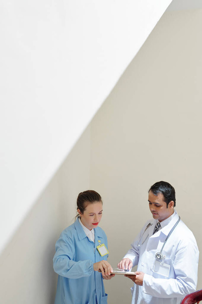 Médicos discutiendo la historia clínica del paciente con enfermedad grave
 - Foto, imagen