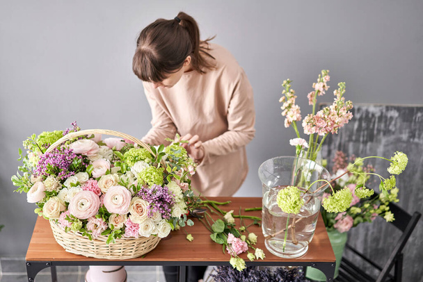 Концепція квіткового магазину. Квіткова жінка створює квіткову композицію в плетеному кошику. Прекрасний букет змішаних квітів. Гарний свіжий букет. Доставка квітів
. - Фото, зображення