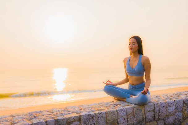 Portré fiatal ázsiai nő nem meditáció körül tenger tengerpart óceán napkeltekor az egészség - Fotó, kép