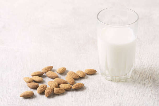 Vegan dairy free almond milk and almonds on white wooden background. Selective focus, space for text. - Fotó, kép