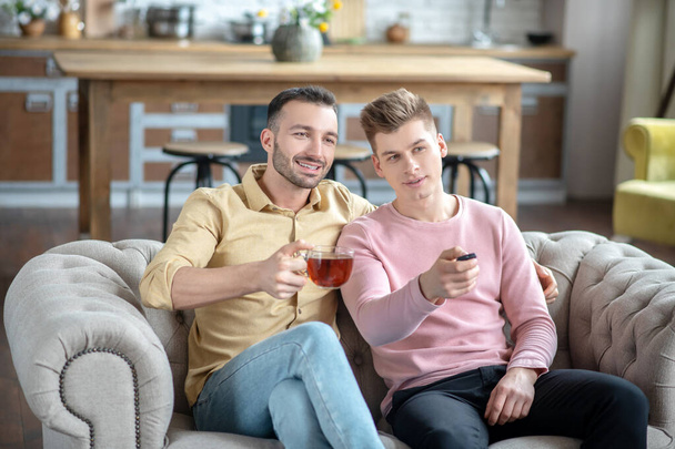 Two young men having tea and feeling happy - Фото, изображение