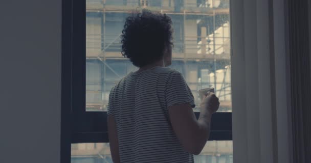 Young man drinking coffee by window in city - Materiał filmowy, wideo