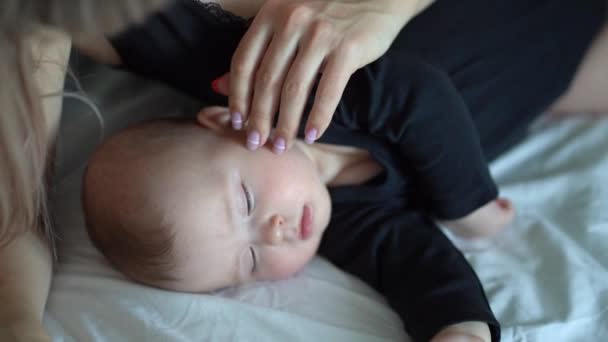the mother stroking the head of a sleeping baby - Felvétel, videó