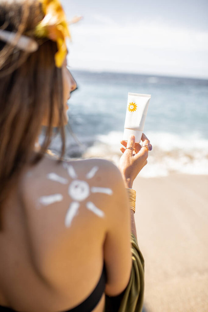Mujer con crema solar en la playa
 - Foto, imagen