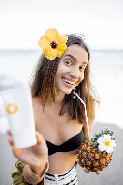 Woman with sunscreen lotion on the beach - Fotó, kép