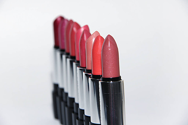 Multicolored lipsticks stand in a heap close-up on a white background. a set of multi-colored lipsticks stand in a row, red, brown, orange, pink, all lipsticks on a white background - Foto, imagen