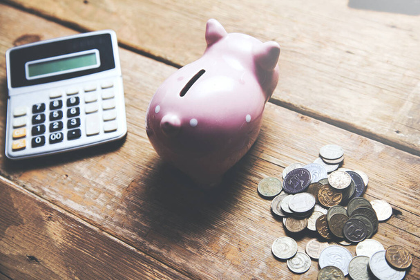 Sparschwein mit Taschenrechner und Münzen auf dem Tisch - Foto, Bild