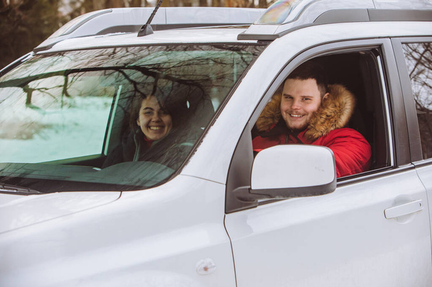 Man en vrouw in de auto in winterkleding. roadtrip - Foto, afbeelding