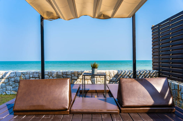 Almohada en sofá cama con salón alrededor de la playa océano mar y cielo azul para vacaciones de viaje
 - Foto, Imagen