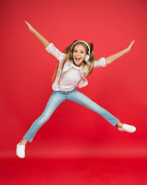 childhood happiness. happy kid listen music. freedom and success. Little girl in earphones. reach her dream. fly up in air. going crazy. excited small girl wear headset. dance with favorite song - Zdjęcie, obraz