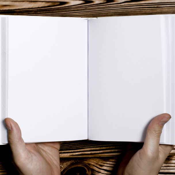 Manos de hombre sosteniendo libro abierto con tapa en blanco sobre fondo claro. Burla del libro cuadrado en blanco abierto
 - Foto, Imagen